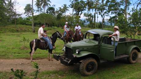 family on horses stops to talk with parents in old truck